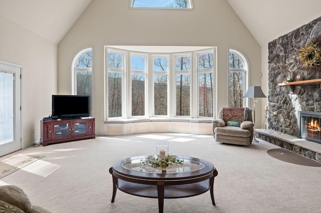 carpeted living area featuring a fireplace and high vaulted ceiling