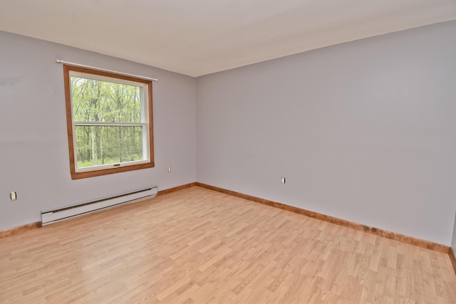 empty room with a baseboard radiator, light wood finished floors, and baseboards