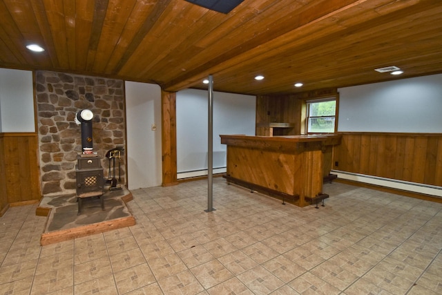 indoor dry bar with a baseboard radiator, wood walls, wainscoting, wood ceiling, and a wood stove