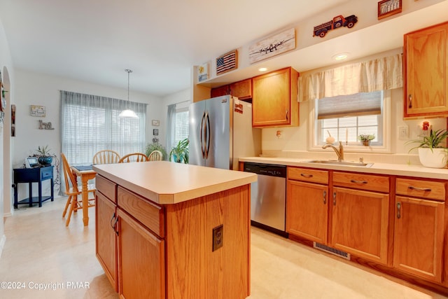 kitchen featuring stainless steel appliances, a kitchen island, a sink, visible vents, and light countertops