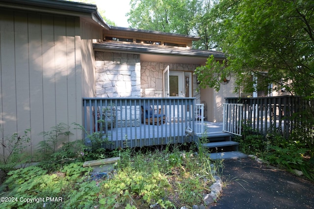 property entrance featuring stone siding and a deck