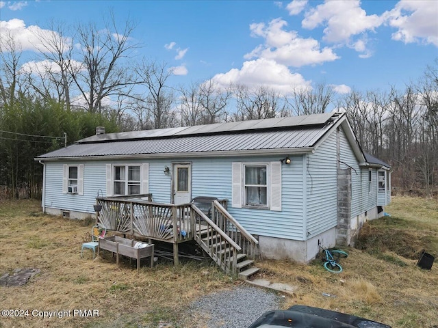 view of front of property featuring roof mounted solar panels, cooling unit, metal roof, and a deck