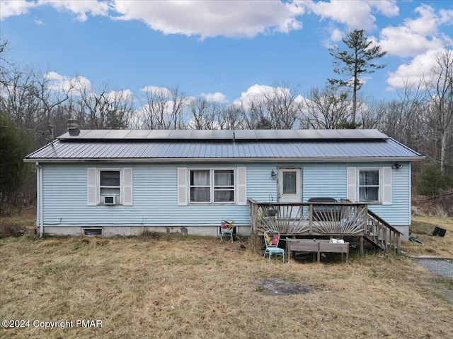 view of front of property featuring metal roof, cooling unit, solar panels, and a deck