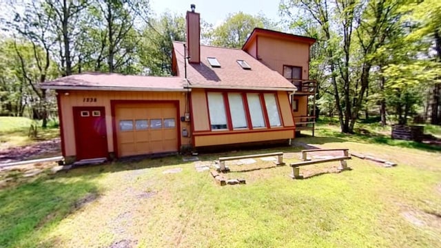rear view of house featuring a chimney, an attached garage, dirt driveway, a balcony, and a lawn