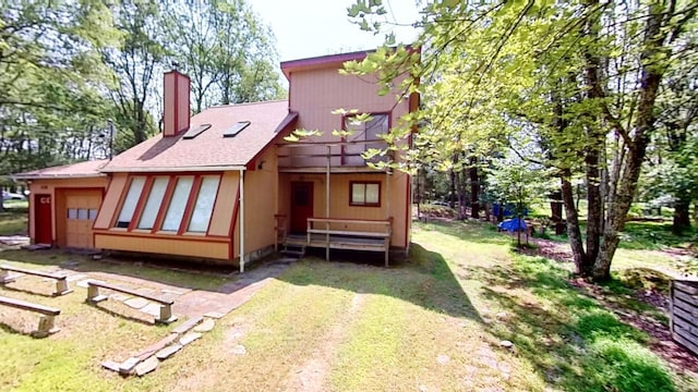 back of house featuring a chimney and a lawn