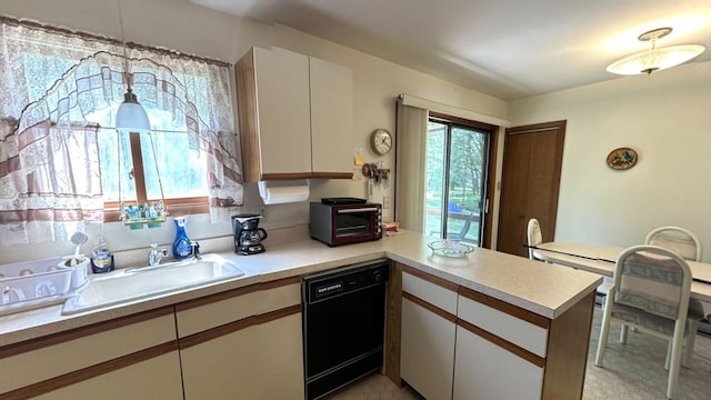 kitchen with black dishwasher, light countertops, a peninsula, white cabinetry, and a sink