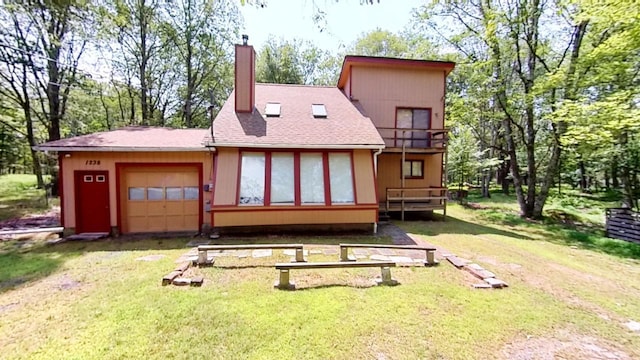 back of property featuring a chimney, a yard, a garage, and a balcony