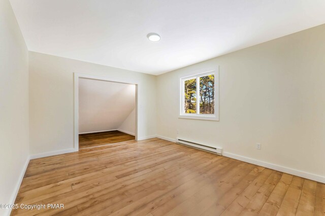 empty room with a baseboard radiator and light hardwood / wood-style floors