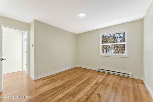 unfurnished room with a baseboard heating unit and light wood-type flooring