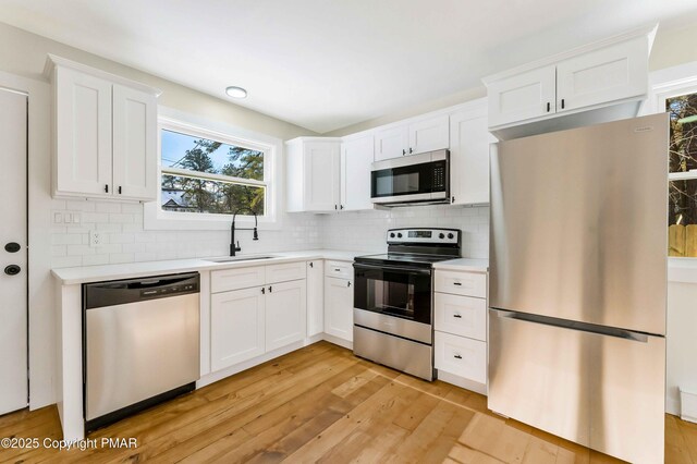 kitchen with white cabinetry, sink, light wood-type flooring, and appliances with stainless steel finishes