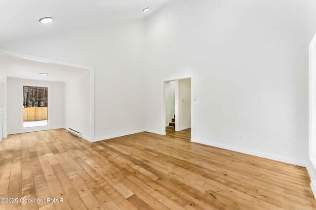 unfurnished living room with light hardwood / wood-style flooring, high vaulted ceiling, and baseboard heating