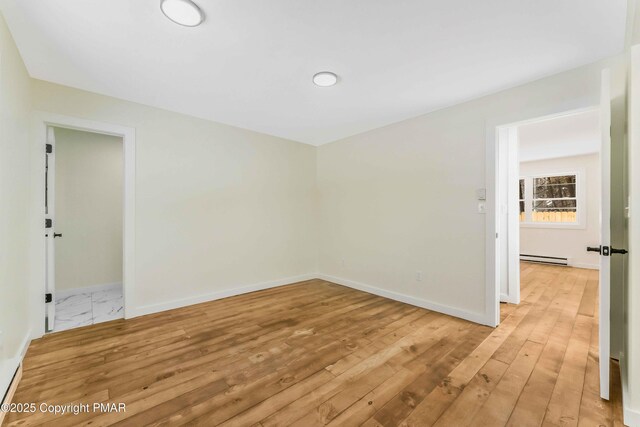 unfurnished room with a baseboard radiator and light hardwood / wood-style flooring