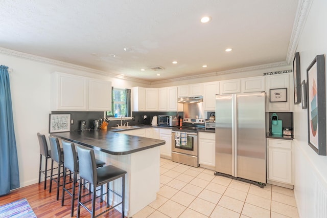 165 Stillwater Dr, Pocono Summit, PA 18346 - kitchen with stainless steel appliances, a sink, under cabinet range hood, dark countertops, and a peninsula