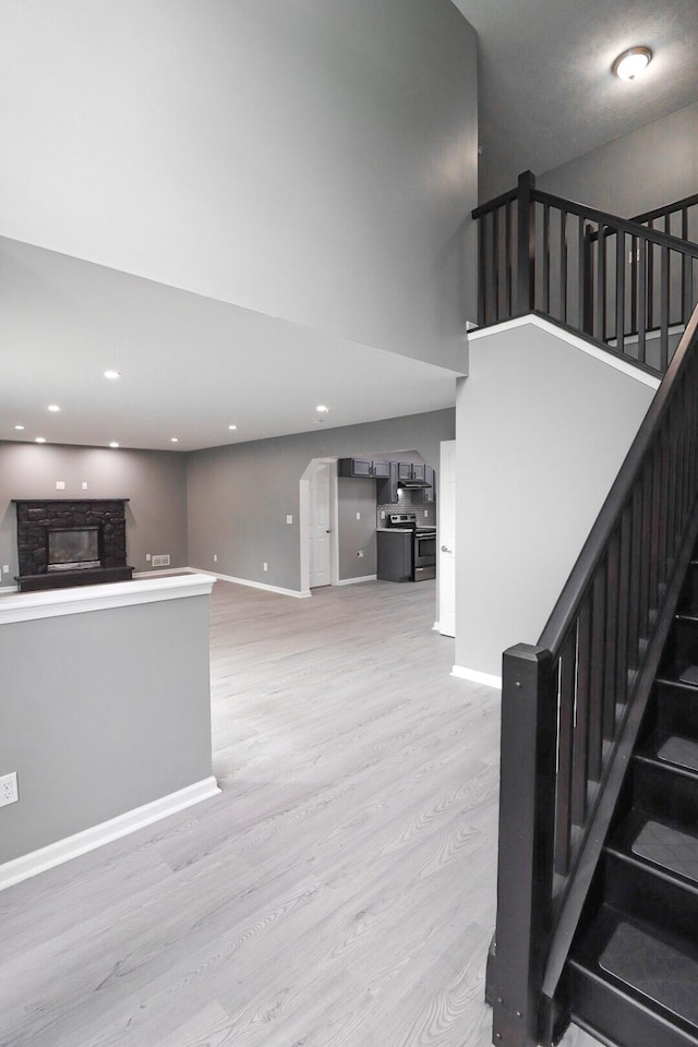 302 Leaf St, Tobyhanna, PA 18466 - unfurnished living room with light wood-type flooring, stairway, a stone fireplace, a towering ceiling, and recessed lighting