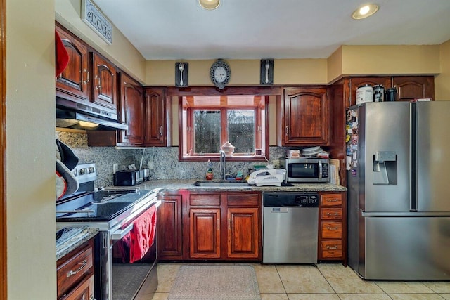 kitchen featuring light stone counters, a sink, stainless steel appliances, under cabinet range hood, and tasteful backsplash