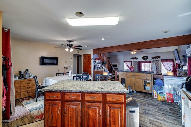 kitchen with beam ceiling, a kitchen island, wood finished floors, and a ceiling fan