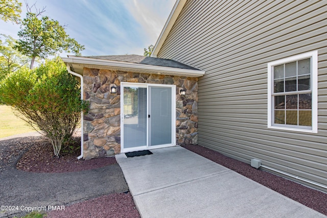 property entrance with stone siding and a shingled roof