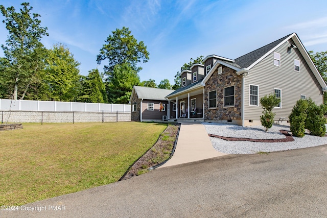 view of front of property featuring a porch, fence, stone siding, crawl space, and a front yard