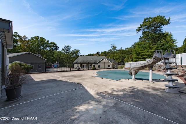 view of pool with a patio, a water slide, fence, and a fenced in pool