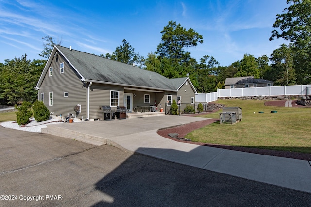 rear view of house featuring driveway, fence, and a lawn