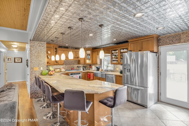 kitchen featuring a peninsula, an ornate ceiling, brown cabinets, and stainless steel appliances