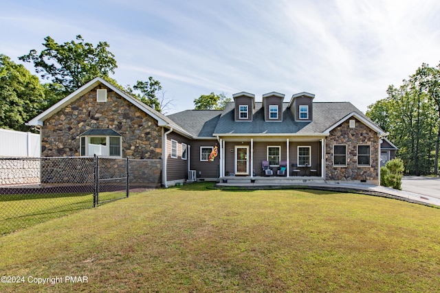 view of front of property featuring a shingled roof, covered porch, fence, cooling unit, and a front lawn