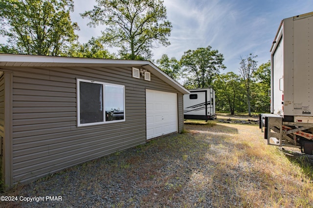 view of yard featuring a garage, driveway, and an outdoor structure