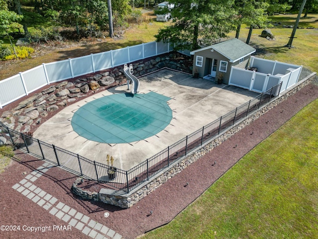 view of pool featuring an outbuilding, a yard, a patio area, and fence