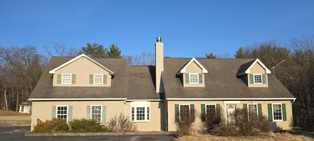 cape cod home featuring a chimney and a shingled roof