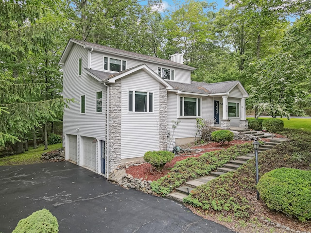106 Legends Ct, East Stroudsburg, PA 18302 - traditional-style house with a chimney, driveway, a garage, roof with shingles, and view of scattered trees