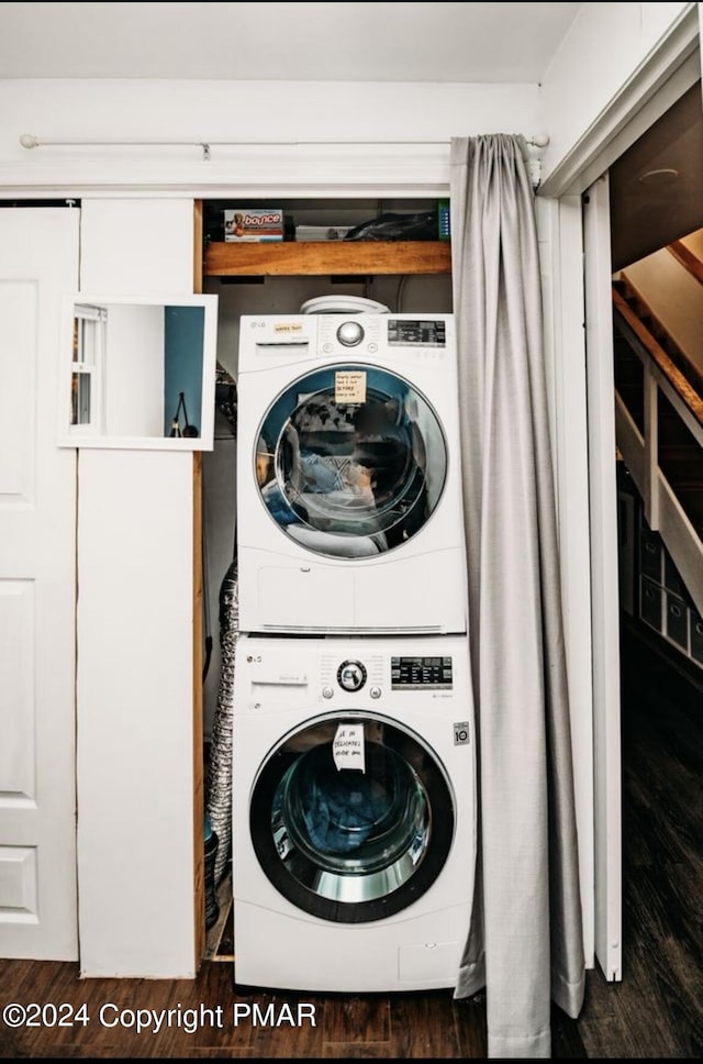 laundry room featuring laundry area, stacked washer / drying machine, and wood finished floors