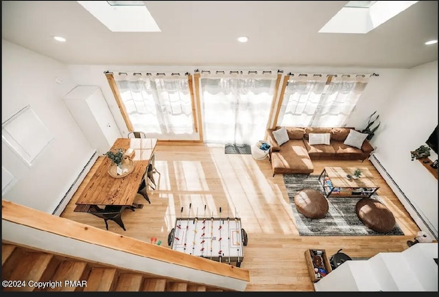 living area with a baseboard heating unit, baseboard heating, a skylight, and wood finished floors