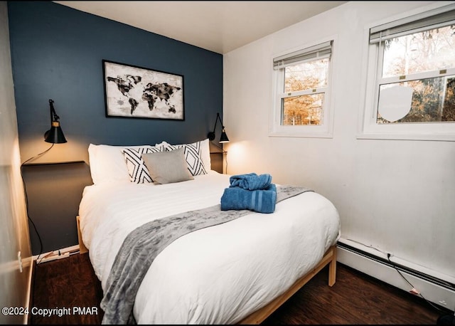 bedroom with a baseboard heating unit and wood finished floors