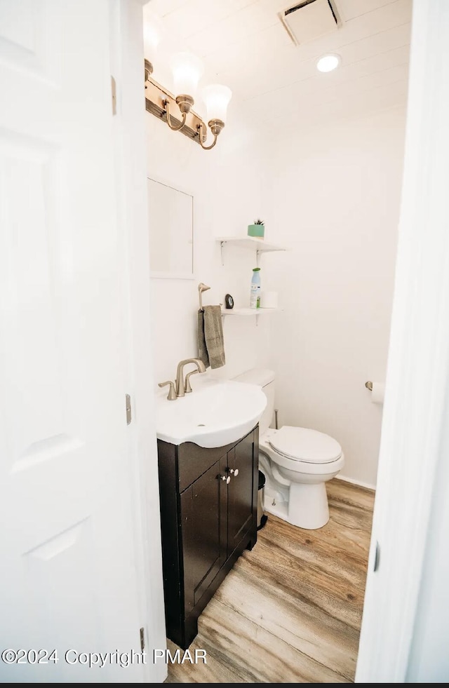 bathroom with toilet, visible vents, wood finished floors, and vanity