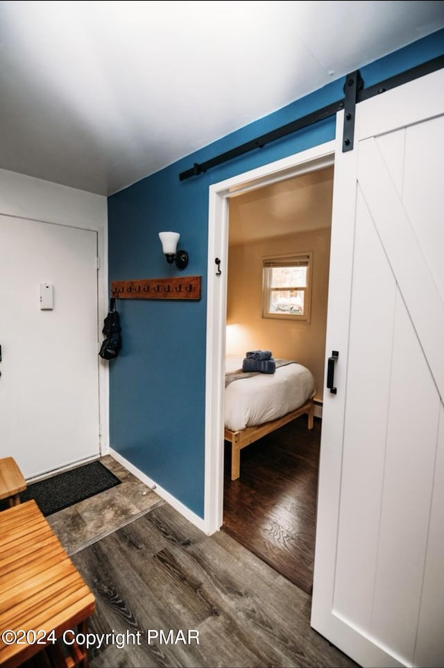 interior space with wood finished floors, baseboards, and a barn door