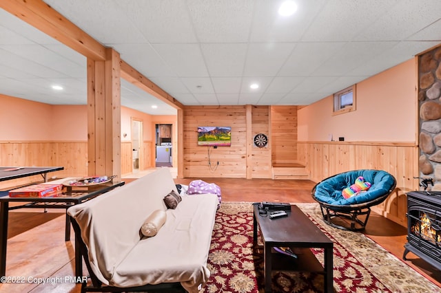 living area with wooden walls, a wainscoted wall, a wood stove, a paneled ceiling, and recessed lighting