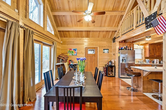 dining area with wooden ceiling, wood walls, light wood-type flooring, and beam ceiling