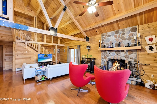 living room with a stone fireplace, wooden ceiling, wood walls, wood finished floors, and beamed ceiling