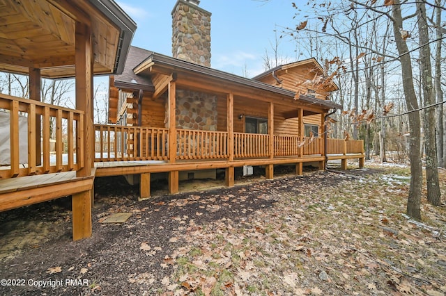 rear view of house with a shingled roof, a chimney, and a deck