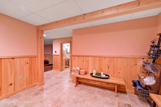 interior space featuring wooden walls, a drop ceiling, and wainscoting