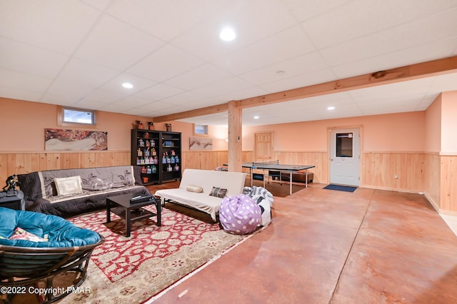 living room with a paneled ceiling, recessed lighting, finished concrete floors, wainscoting, and wooden walls