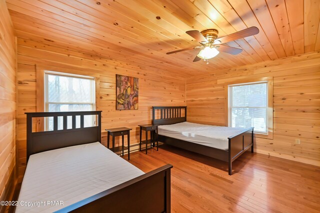 bedroom featuring multiple windows, wood ceiling, and wooden walls