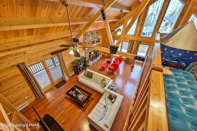 living area with visible vents, beamed ceiling, wooden walls, and wood finished floors