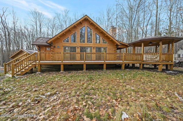 back of property with a deck, a yard, a chimney, and log siding