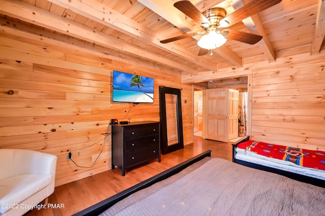 bedroom with wood ceiling, wooden walls, beamed ceiling, and wood finished floors