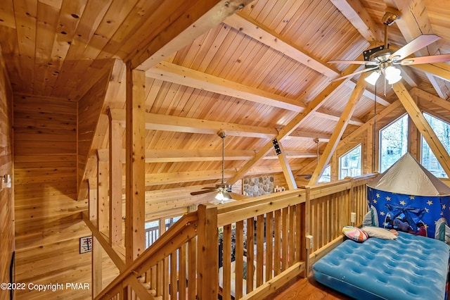 interior space featuring vaulted ceiling with beams, a ceiling fan, wood ceiling, wooden walls, and wood finished floors