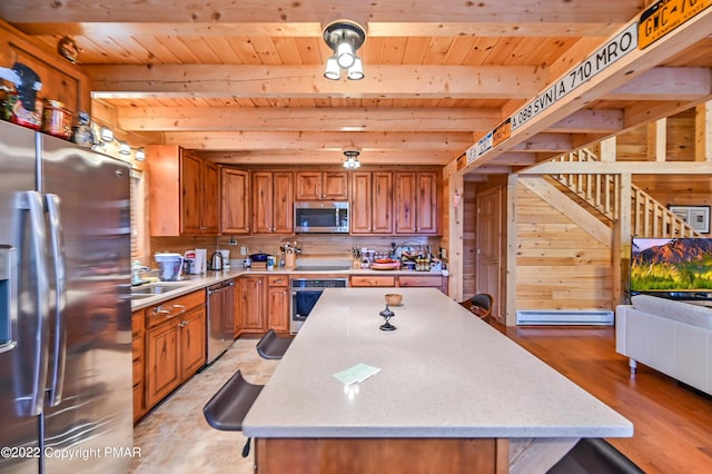 kitchen featuring wooden ceiling, stainless steel appliances, beam ceiling, and a center island