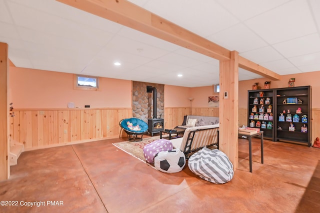 workout room featuring a paneled ceiling, recessed lighting, a wood stove, wainscoting, and wood walls