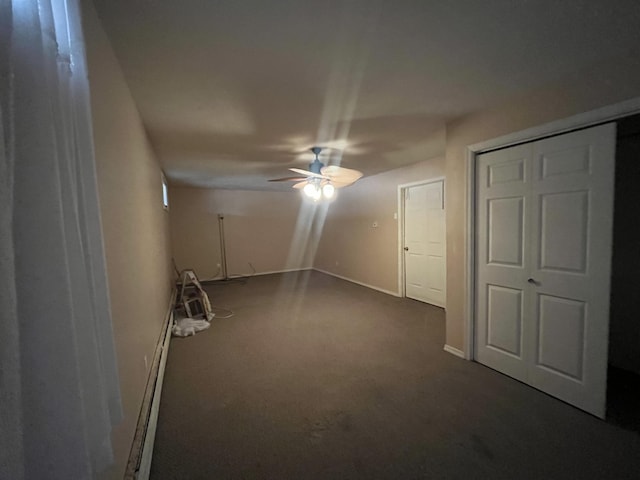 interior space with dark colored carpet, a baseboard heating unit, baseboards, and a ceiling fan