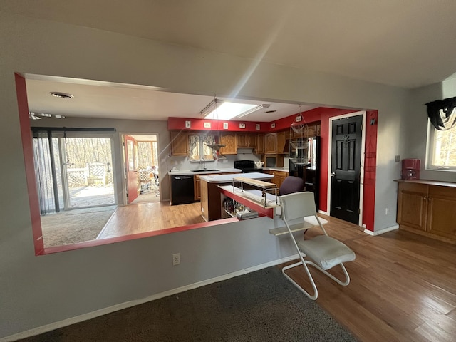 kitchen featuring baseboards, light wood-style floors, range with electric stovetop, dishwasher, and a center island